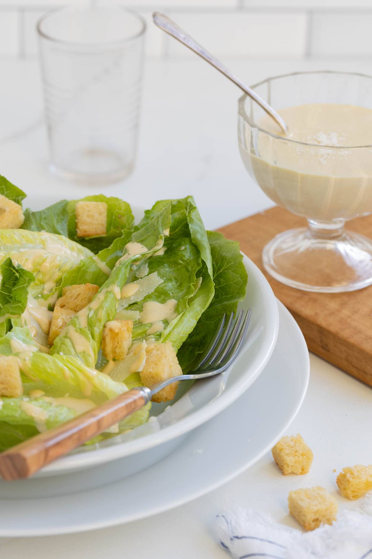 Caesar salad  in bowl with homemade dressing on side.