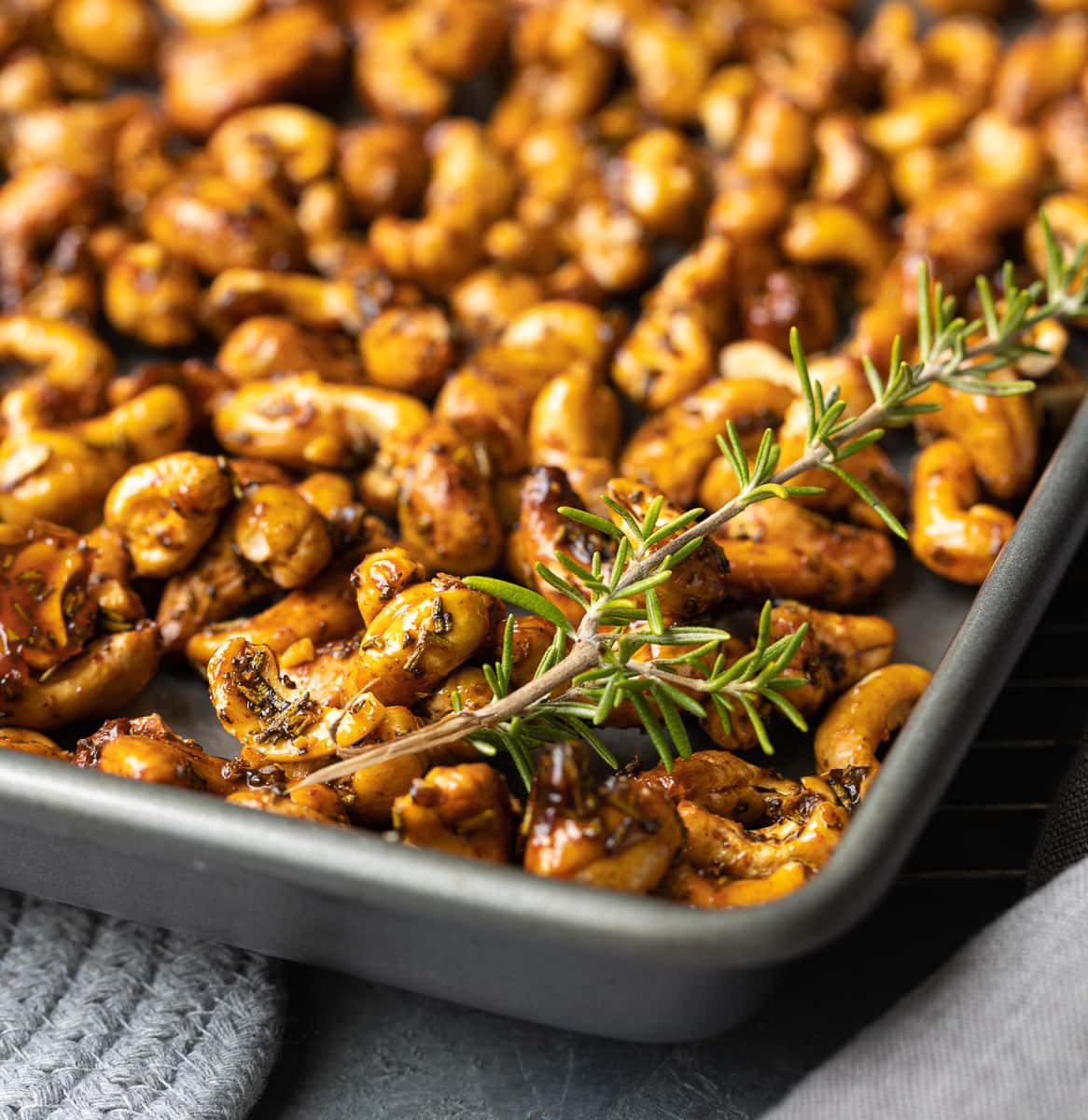 Closeup of roasted maple cashews with rosemary.