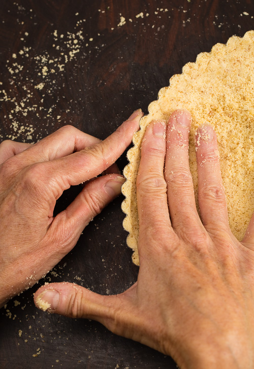 Creating the tart crust with your fingers, pressing around the edge of the the tart pan.