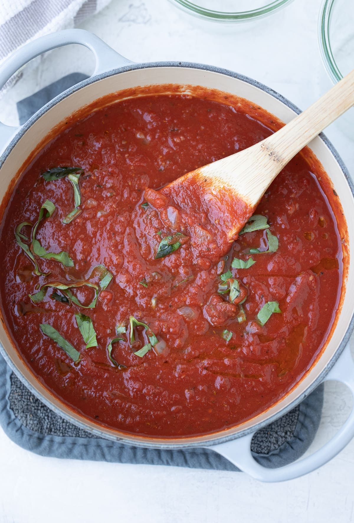 Finished homemade tomato marinara in a pot with basil leaves.