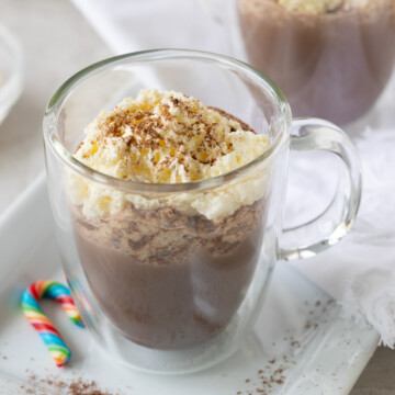 Glass mug of hot chocolate with whipped cream.