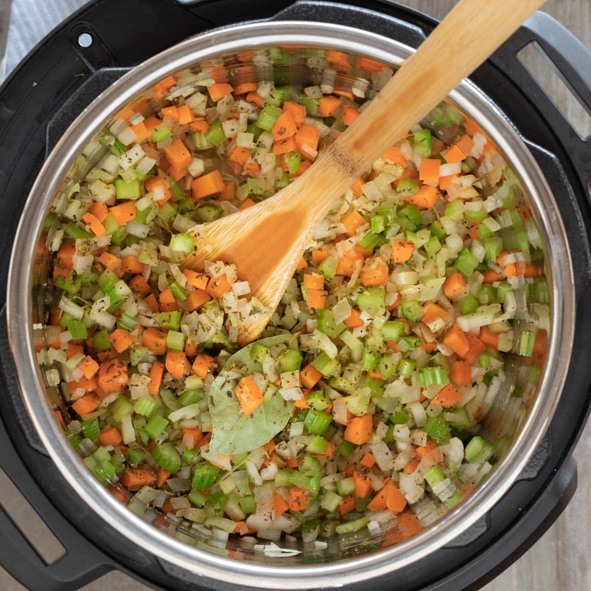 Vegetables sautéing in an Instant Pot before pressure cooking lentil soup.