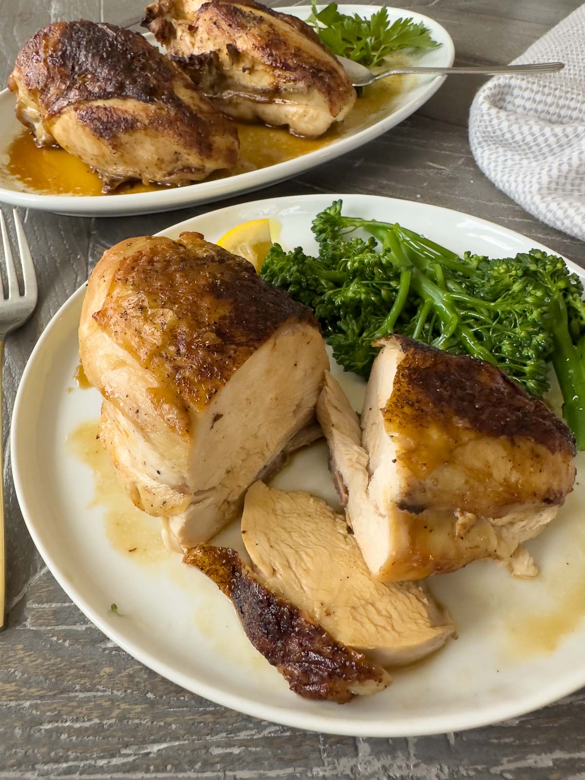 Roast chicken breast on plate, sliced to eat, with broccolini.