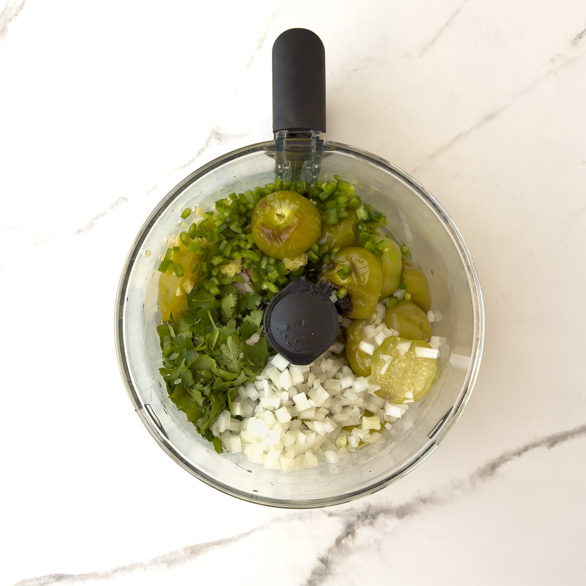 Ingredients for salsa verde in a food processor bowl.