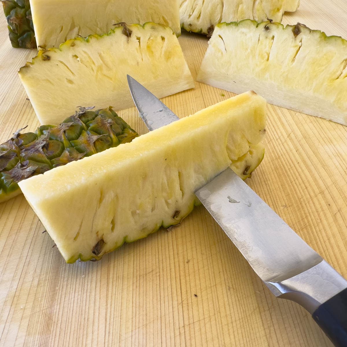 Cutting the tough skin off of pineapple spears.