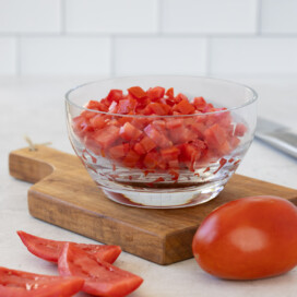 Diced red tomatoes in a glass bowl on a the counter.