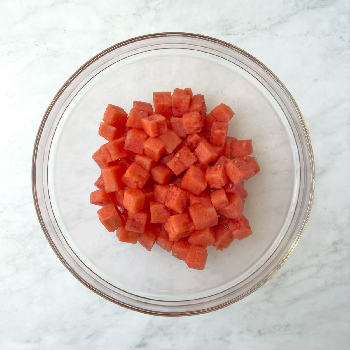 Red watermelon cubes in a glass bowl.