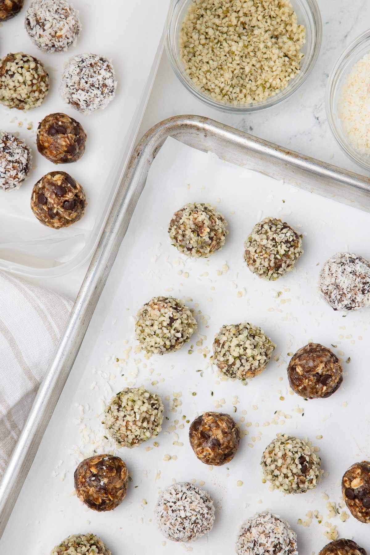A baking sheet of rolled protein balls finished with coconut, help seeds, and plain.