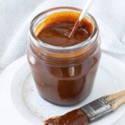 A glass jar of deep red homemade bbq sauce.