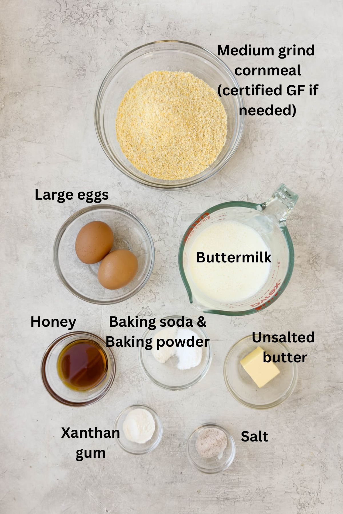 Ingredients in prep bowls on a kitchen counter for making cornbread.