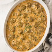 Creamy casserole dish of beef stroganoff made with meatballs with herbs on top.
