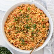 A bowl of colorful rice with mixed vegetables and a parsley garnish ready to serve.
