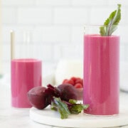Beautiful bright pink red beet smoothies in tall glasses with red beets on the side.