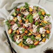 Colorful summer salad or burrata cheese, golden peaches, greens, basil, and balsamic dressing.