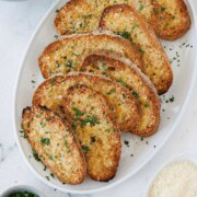 Golden cheesy gluten free garlic toast on a platter.
