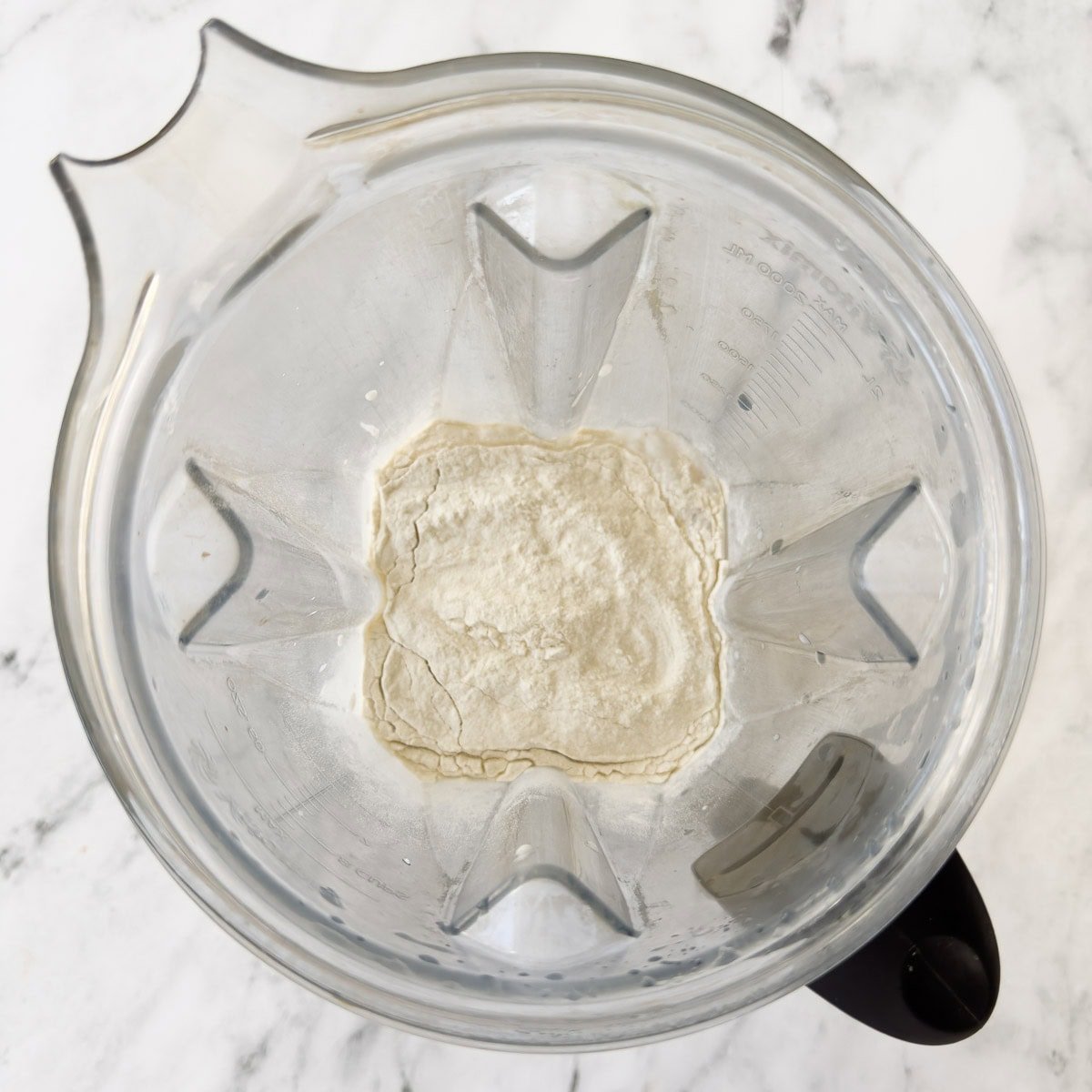 A blender container with milk and protein powder inside.