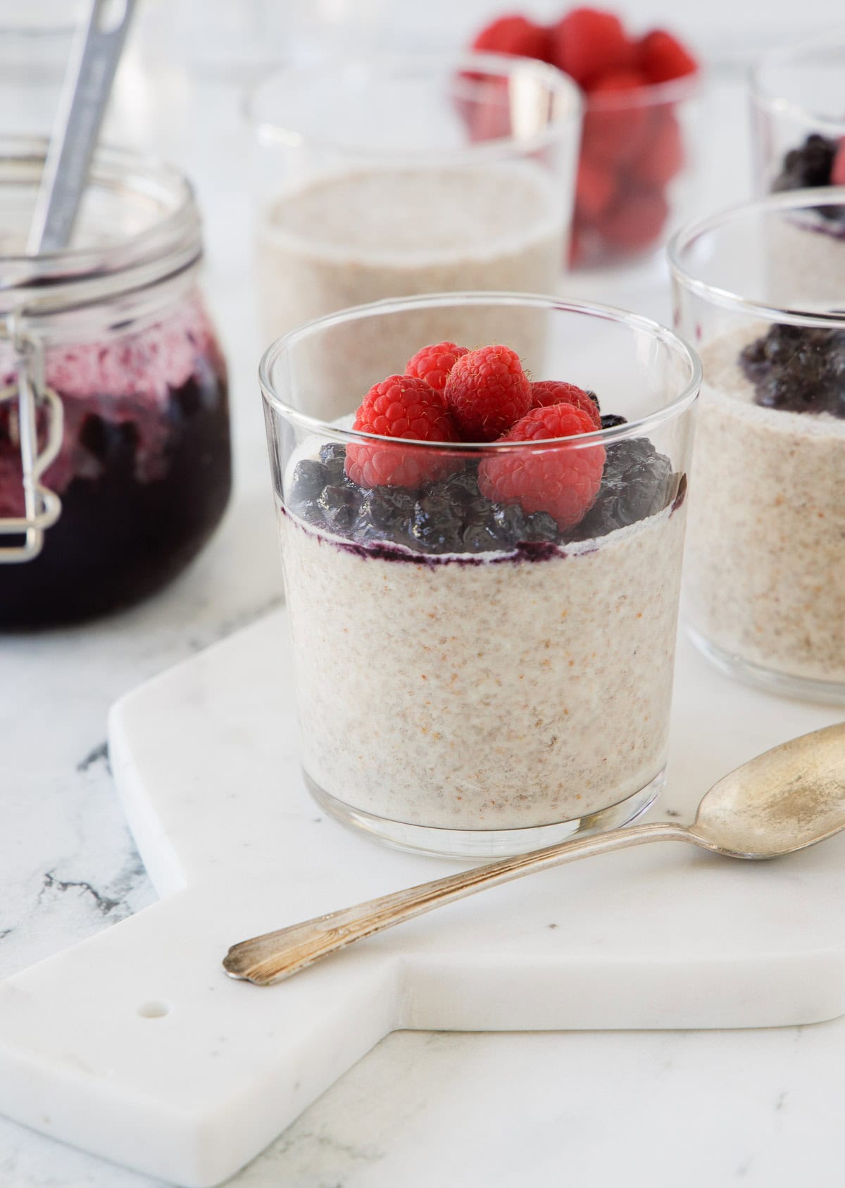 Glasses of chia pudding with coconut milk topped with blueberries and raspberries.