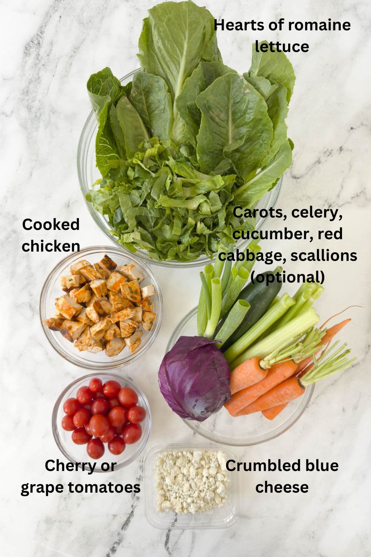 Ingredients for a buffalo chicken salad with carrots, celery, tomatoes, and romaine.