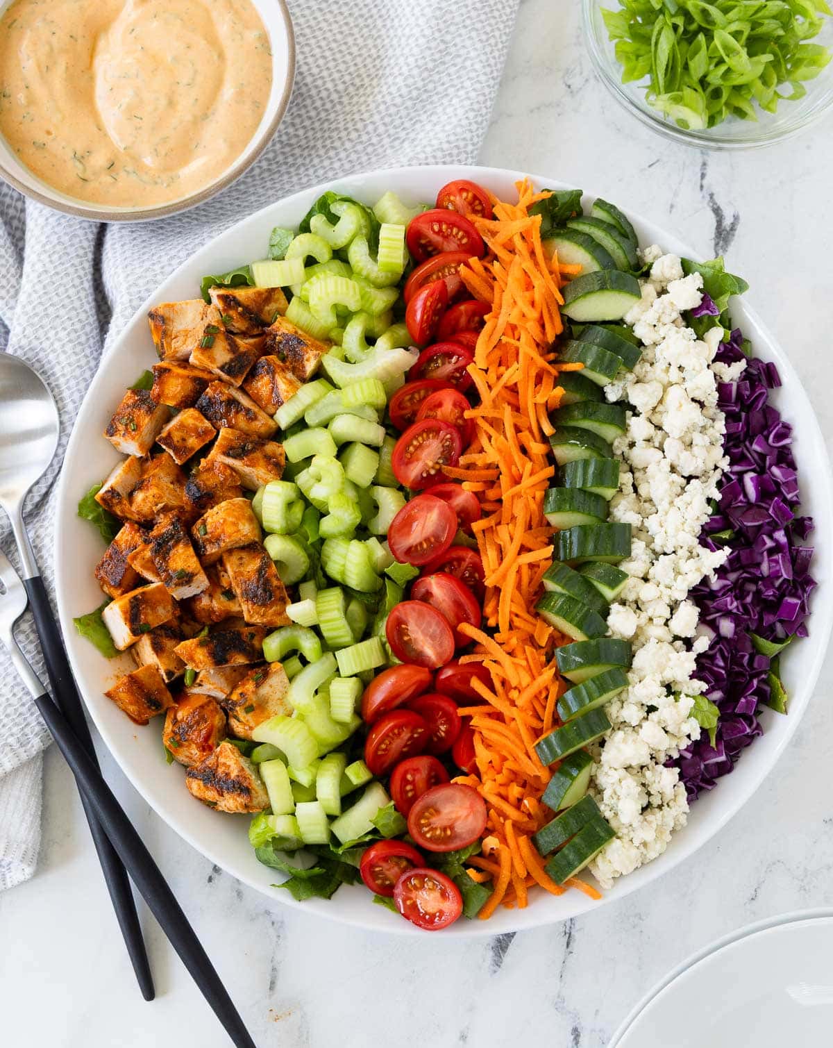 Buffalo chicken salad arranged in colorful rows, with chicken, tomatoes, celery, blue cheese, and carrots.