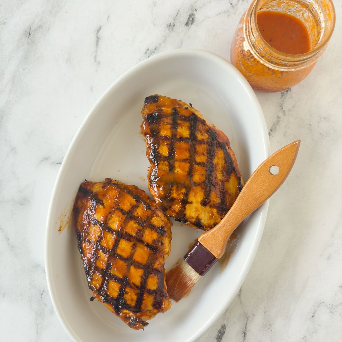 Griled chicken breasts with perfect grill marks, pastry brush, and marinade jar. 