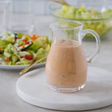 A small glass pitcher of buffalo ranch dressing ready to pour over salad greens.