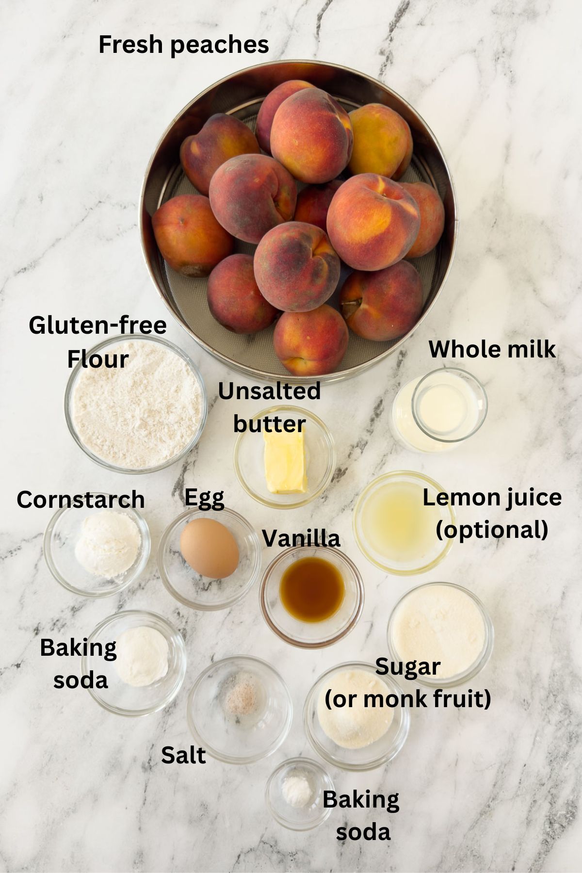 Ingredients for a peach cobbler in prep bowls on a marble counter.
