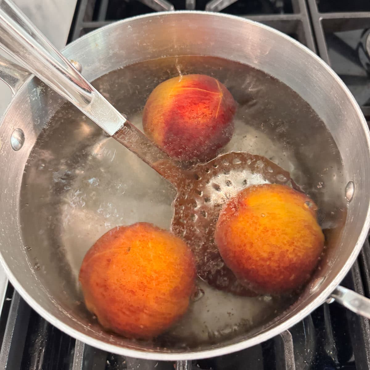 A pot of boiling water with peaches blanching for peeling.