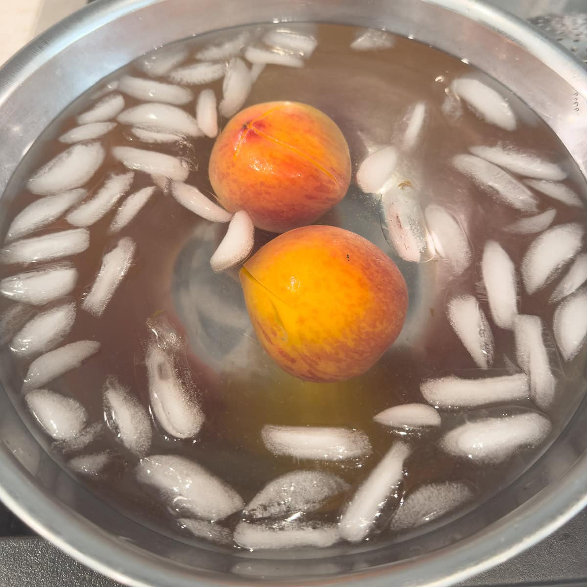 Peaches in an ice bath chilling for peeling.