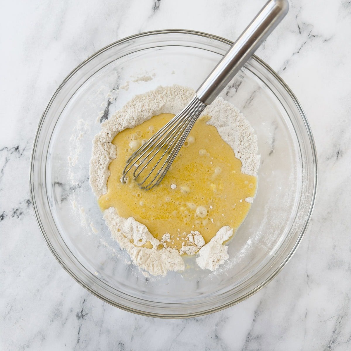 Wet and dry ingredients being whisked together to create a batter.