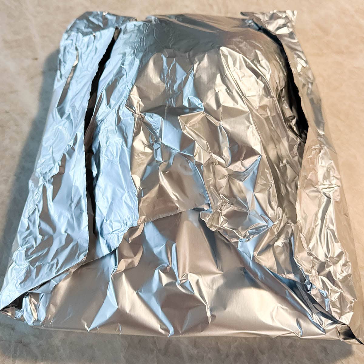 A foil covered turkey breast resting before carving. 