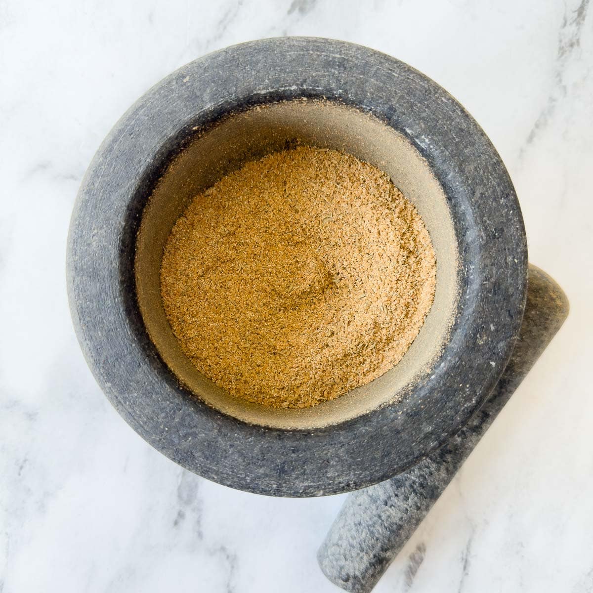 Turkey seasoning rub blended together in a gray mortar and pestle.