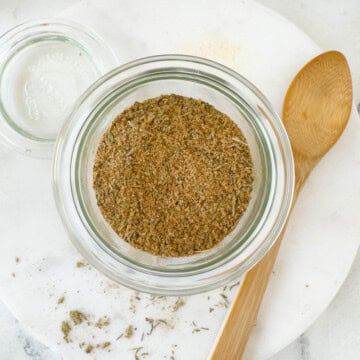 A jar of blended turkey rub ready to go for use with a woodem spoon.