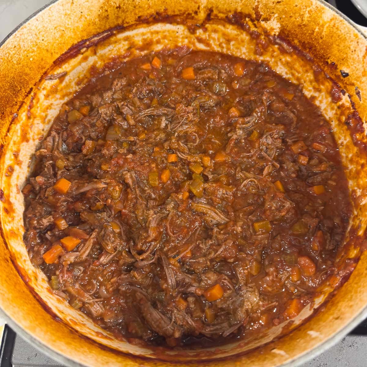 Shredded Italian short rib ragu in a dutch oven, ready to serve