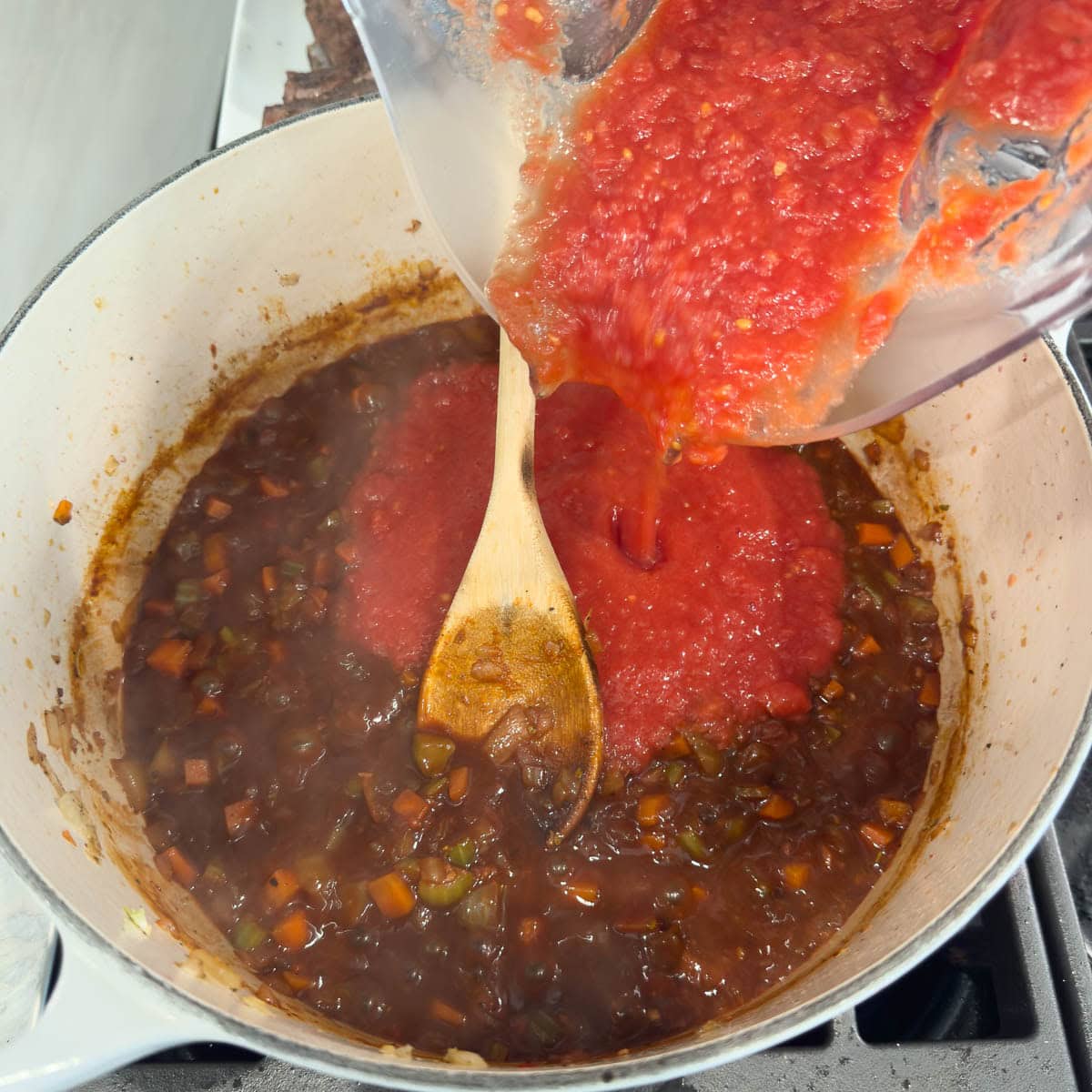 Bright red pureed tomatoes being poured into a pot. 