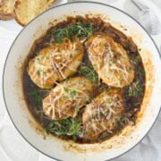 Four golden chicken breasts topped with caramelized onions, herbs, and melting cheese.