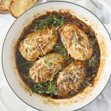 Four golden chicken breasts topped with caramelized onions, herbs, and melting cheese.