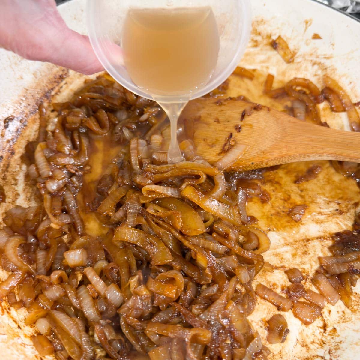 Add broth to a pan of caramelized onions to make sauce.