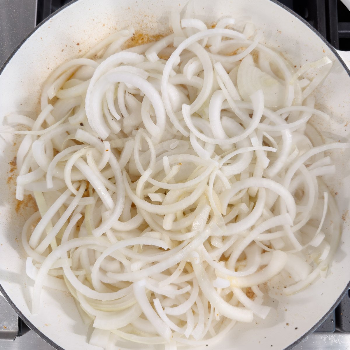 A pan full of sliced onions starting the caramelization process.