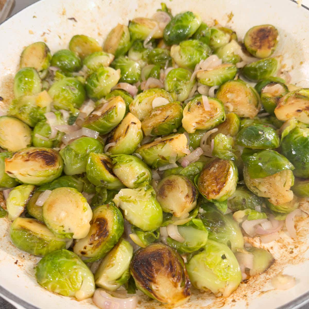 Browned sprouts with pink shallots and galic cooking in a pan.r