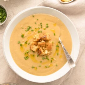 A bowl of creamy, golde leek and potato soups garnished with croutons and olive oil.