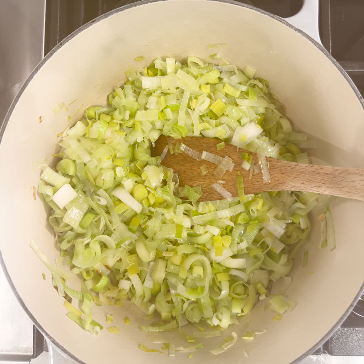 Sauteing chopped leeks in butter in a dutch oven on the stovetop.