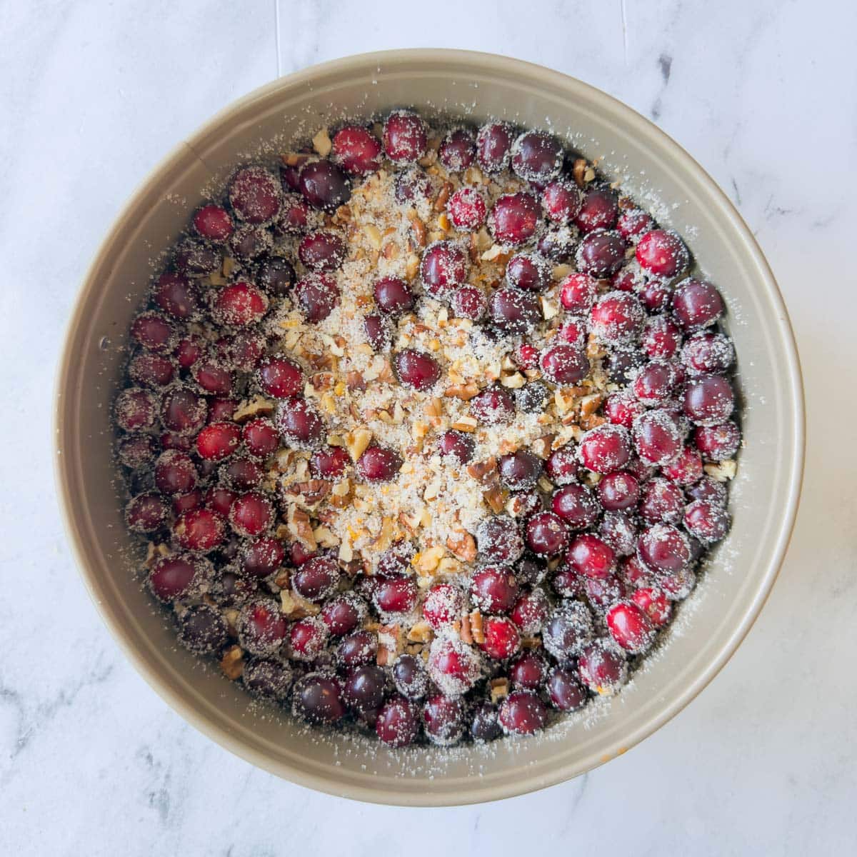 Cranberries, nuts, sugar, and orange zest mixed in a round pan.