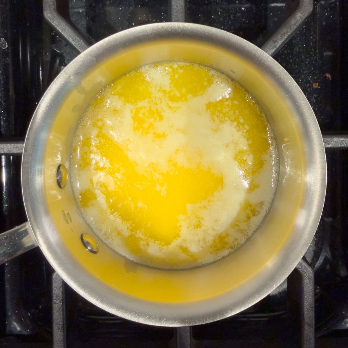 Golden melted butter in a small stainless steel pan.