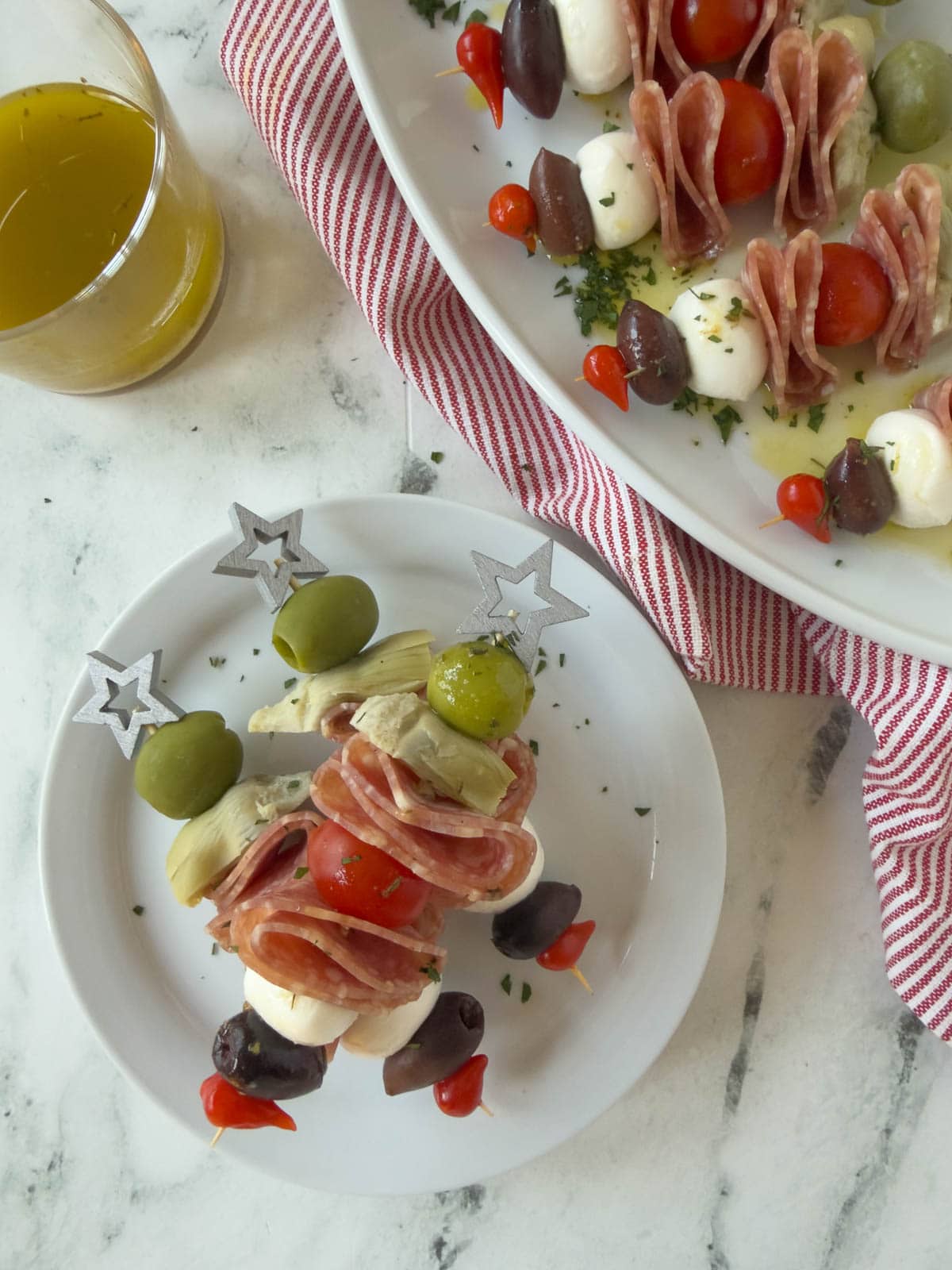 A small plate stacked with antipasto skewers with star tops and dressing.