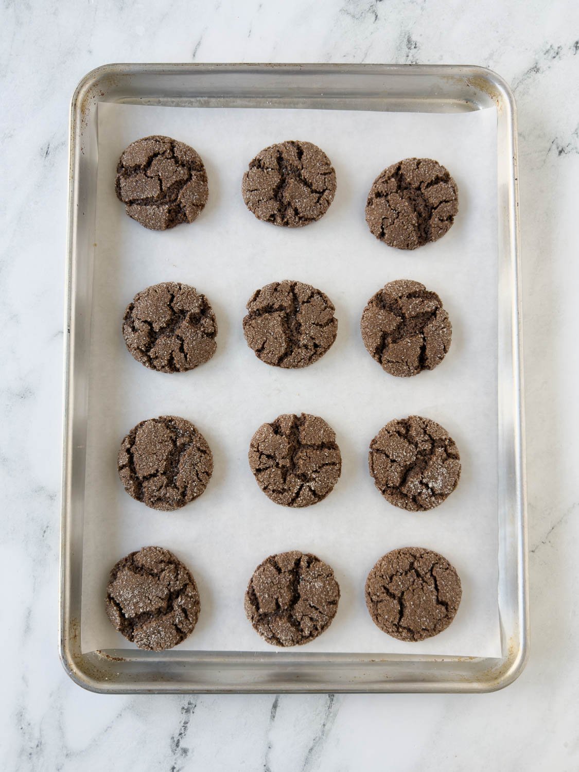 Baked chocolate almond flour cookies on a baking sheet cooling.