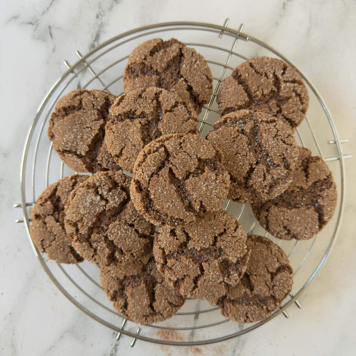 A round wire cooling rack piled with chocolate cookies.