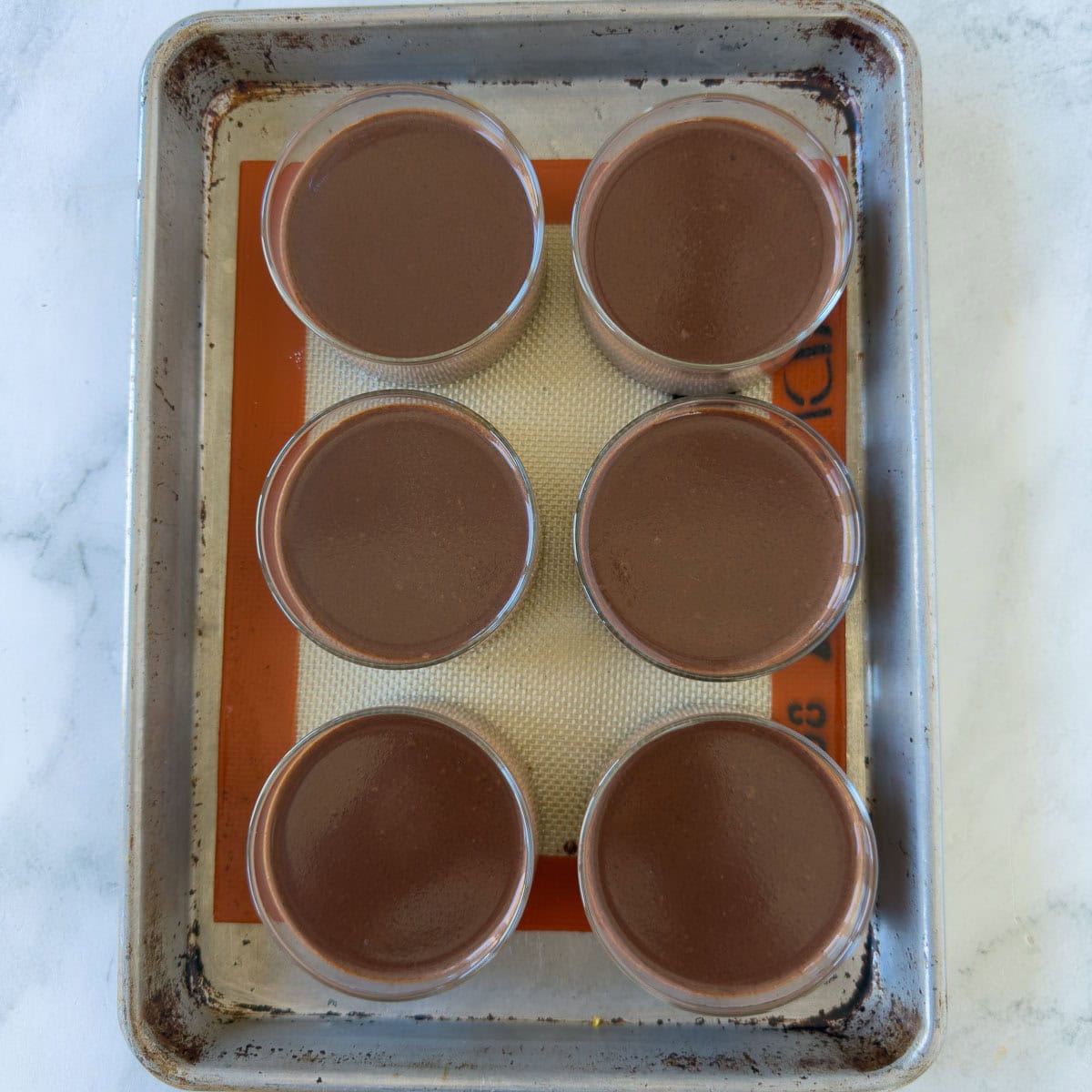 Glass ramekins of chocolate
 panna cotta on a small sheet tray to set up. 