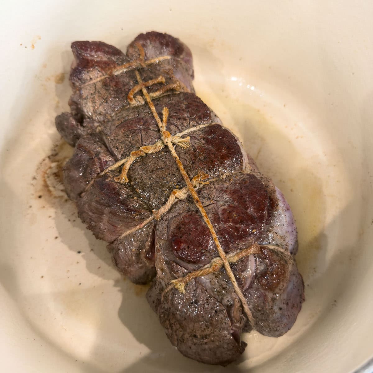 Searing a chuck roast until brown on all sides in a dutch oven.