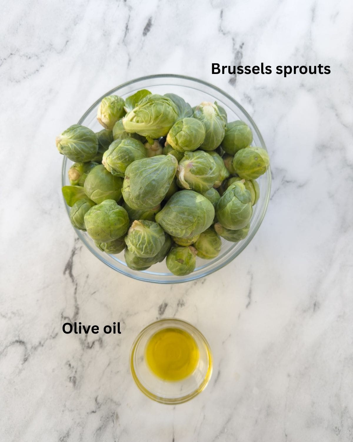 A bowl of bright green raw Brussels sprouts and olive oil for steaming. 