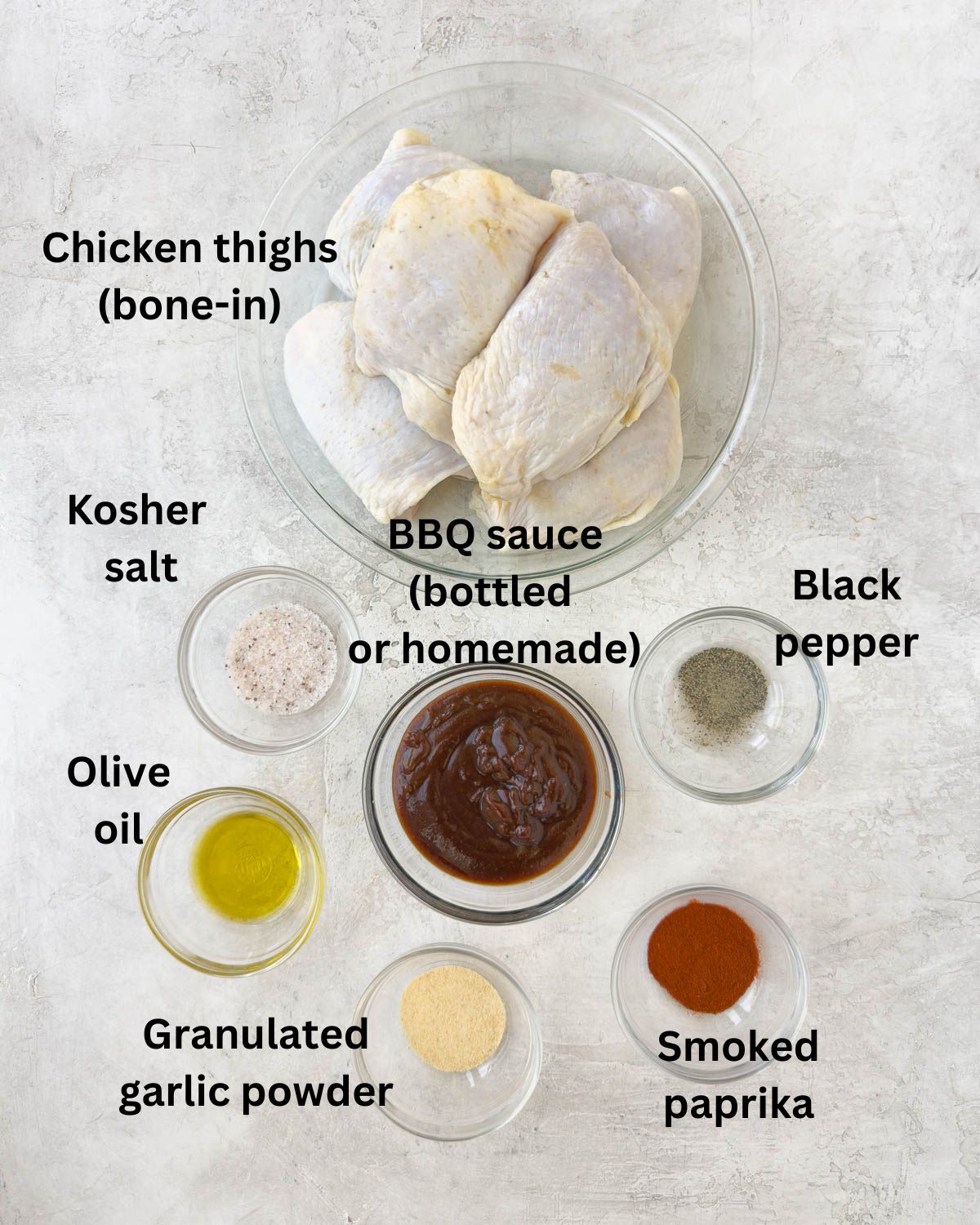 Raw chicken thighs with bbq sauce, and seasonings on a cuonter.